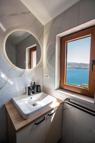 a bathroom with a sink and a mirror and a window at Villa Kamia - Luxury seaview villa with private heated pool in Zubovići