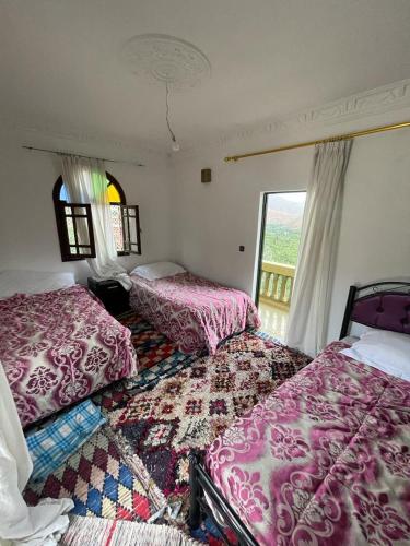a bedroom with two beds and a window with a view at RIAD TOUBKAL D'ATLAS TIFNOUTe in Imlil