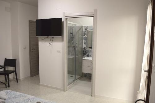 a bathroom with a shower and a television on a wall at Spiaggia LazzarettoHouse in Alghero