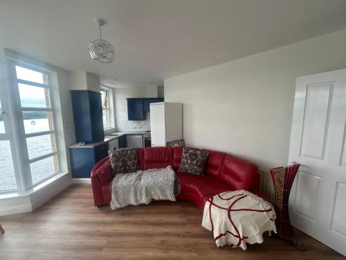 un sofá rojo en la sala de estar con cocina en DANS apartment, en Derry Londonderry