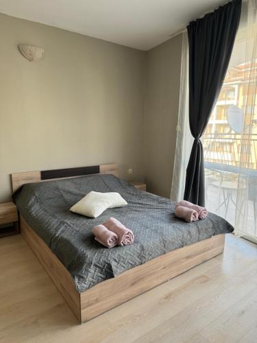 a bedroom with a bed with two pink pillows on it at Студио Мая in Sunny Beach