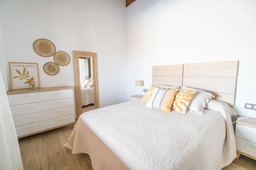 a white bedroom with a large bed and a dresser at Villa olimá in El Gastor