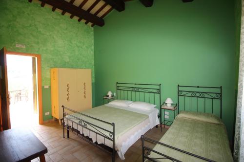 a bedroom with two beds and a green wall at Agriturismo L'Arcadia in Citta' Sant'Angelo