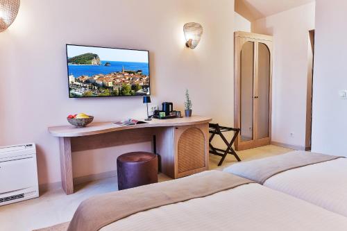 a bedroom with a desk and a tv on the wall at Boutique hotel Ruzmarin SPA & Garden by Aycon in Budva