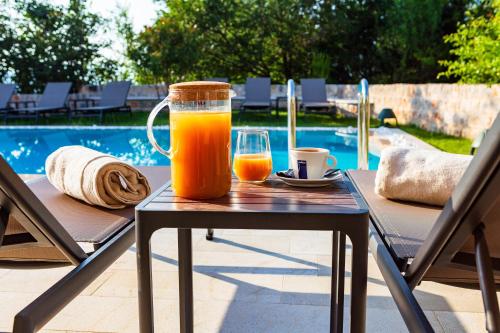 a glass of orange juice on a table next to a pool at Boutique hotel Ruzmarin SPA & Garden by Aycon in Budva