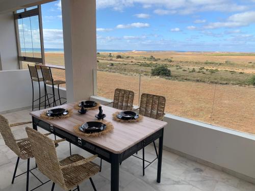 ein Esstisch mit Stühlen und Blick auf die Wüste in der Unterkunft Appartement de luxe avec vue sur mer in Bouznika