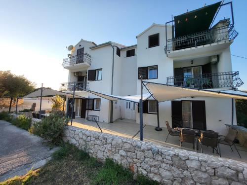 a large white building with a stone wall at Apartments Pitve in Jelsa
