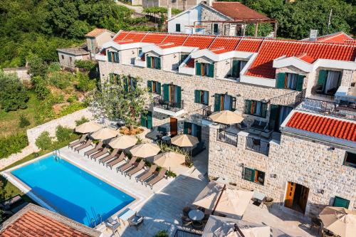an aerial view of a building with a swimming pool and umbrellas at Boutique hotel Ruzmarin SPA & Garden by Aycon in Budva