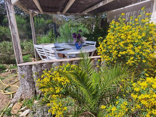 une table et des chaises dans un jardin avec des fleurs jaunes dans l'établissement Le temps de vivre, à Baron