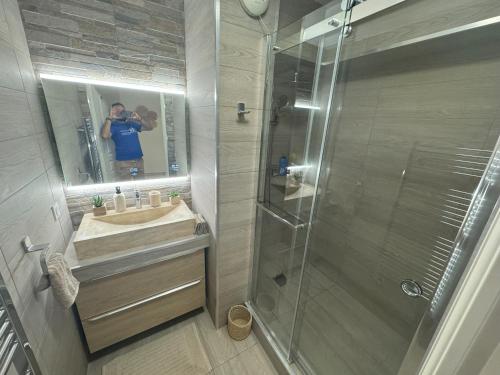un homme prenant une photo d'une salle de bains avec douche dans l'établissement Elegant Apartment with Sea View and Swimming pool, à Nice