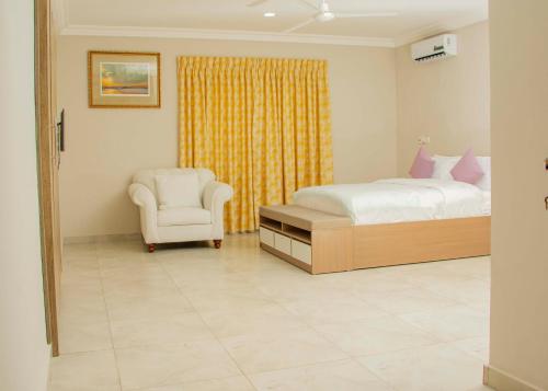 a bedroom with a bed and a chair at Pot of Gold East Legon in Accra