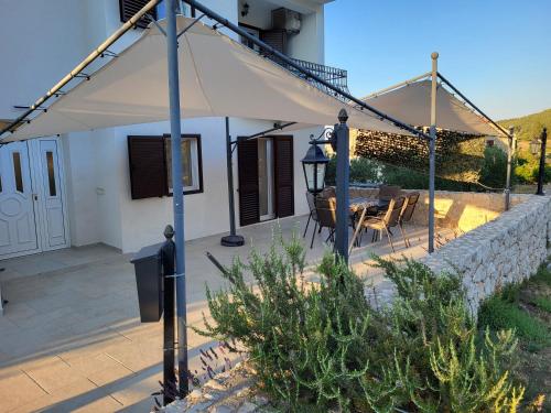 a white umbrella on a patio with a table at Apartments Pitve in Jelsa