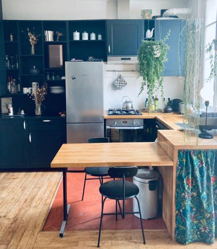 une cuisine avec des placards bleus et une table en bois dans l'établissement Charmant T3 dans les Puces, à Saint-Ouen