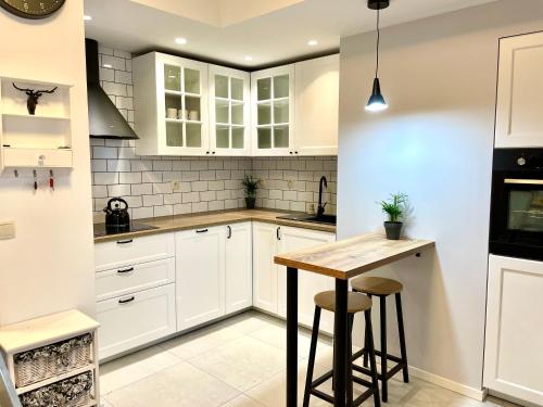 a kitchen with white cabinets and a wooden table at Sonja in Zator