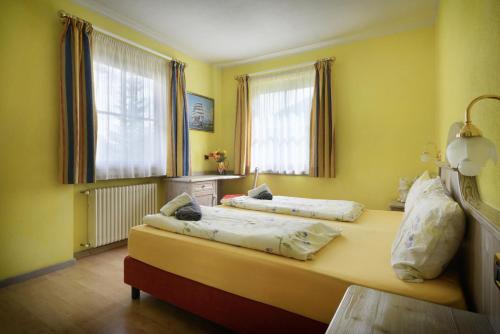 two beds in a room with yellow walls and windows at Residence Le Cascate in Livigno