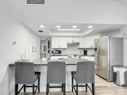 a kitchen with a counter and chairs and a refrigerator at 5 Beds 3 BDR 2 Bath Heated Pool, Grill, Patio in Marco Island