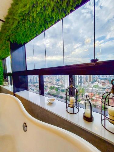 ein Raum mit einem großen Fenster mit Kerzen darauf in der Unterkunft Luxury Collection - Loft com Banheira 33º Ed Vertigo in Campo Grande