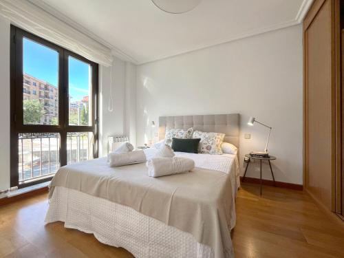 ein weißes Schlafzimmer mit einem großen Bett und einem großen Fenster in der Unterkunft VUT Plaza Fontana in Salamanca