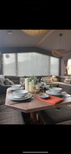 a table with plates and wine glasses on it at Cornwall caravan in Crantock