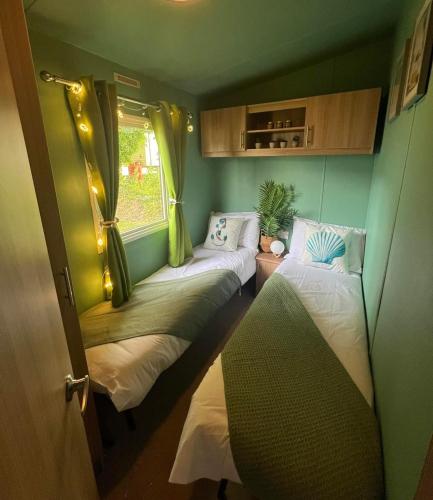 a small room with two beds and a window at Cornwall caravan in Crantock