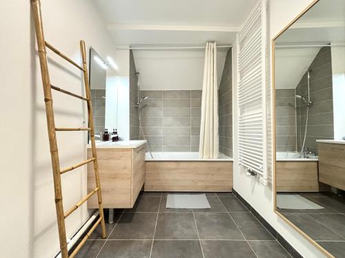 une salle de bain avec une baignoire, un lavabo et un miroir dans l'établissement L Eiffel Disney 5min Paris 35min Parking Terrasse, à Serris