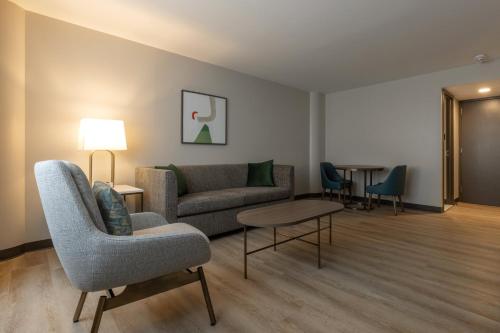 a living room with a couch and a table and chairs at Holiday Inn St-Jean-sur-Richelieu Congrès by IHG in Saint-Jean-sur-Richelieu