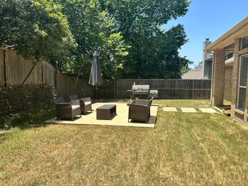 a patio with chairs and an umbrella in a yard at New Spacious 5-bedroom Home for Large Family in Garland