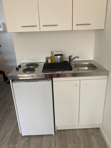 une cuisine avec des armoires blanches et un évier dans l'établissement Le cosy duplex avec jardin à Poitiers, à Poitiers