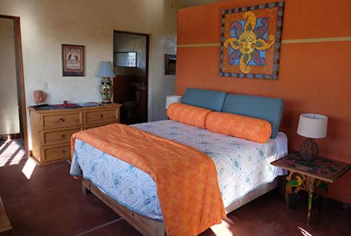 Un dormitorio con una cama con una manta naranja. en The Cozy Nest, en Todos Santos