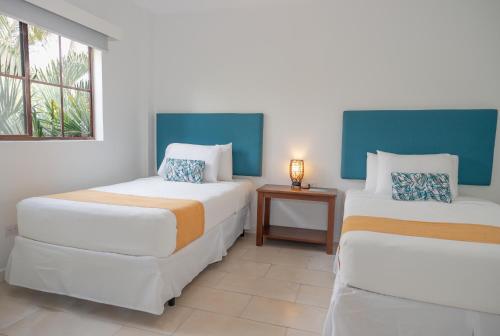 two beds in a room with a table and a window at Hotel Roca Sunzal in La Libertad