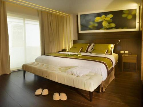 a bedroom with a large bed with a bench next to a window at Oro Verde Loja in Loja