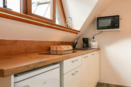 a kitchen with white cabinets and a tv on the wall at Apartamenty Willa Anna in Poronin