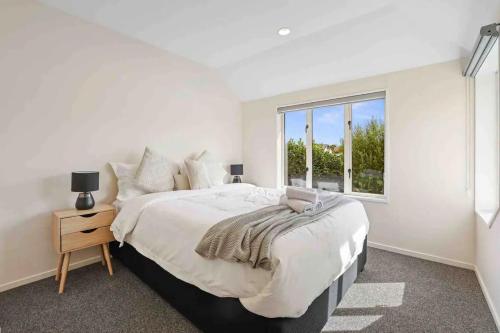a white bedroom with a large bed and a window at A Great Location 4 bedrooms, quiet and comfort! in Christchurch