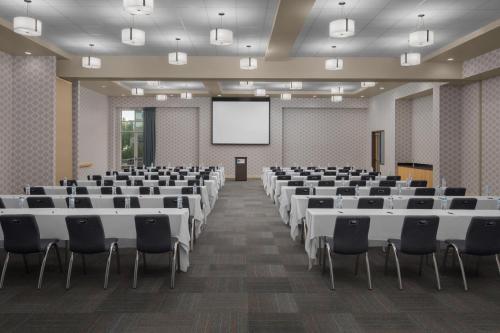 a conference room with tables and chairs and a screen at Aloft Broomfield Denver in Broomfield