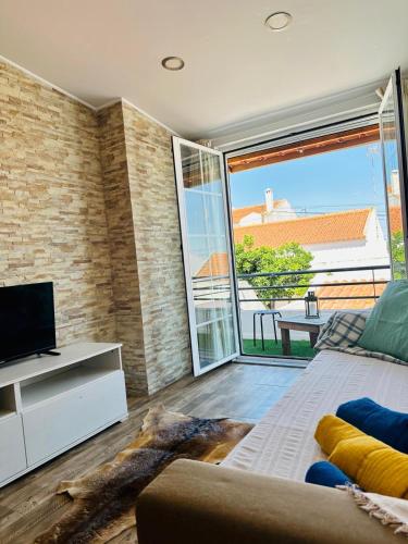 a room with a couch and a tv and a window at Sado Guest House in Alcácer do Sal