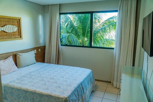 ein Schlafzimmer mit einem Bett und einem großen Fenster in der Unterkunft Marulhos Resort - Conforto e Espaço pra curtir e relaxar in Porto De Galinhas