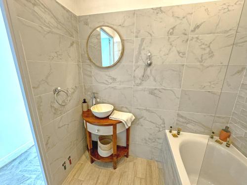 une salle de bain avec un lavabo, une baignoire et un miroir dans l'établissement Milord Promenade 4, à Nice