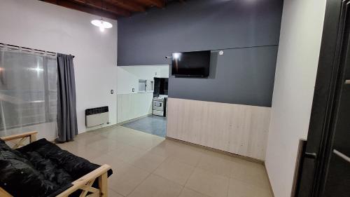 Una sala de estar con un sofá y un televisor en una pared. en Lo de Juancito, en Cipolletti