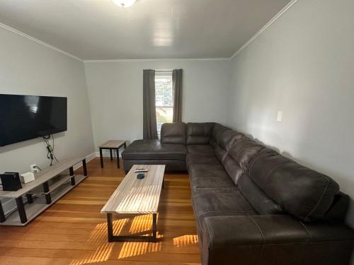 a living room with a leather couch and a coffee table at Strikeout All Star Baseball Rentals in Oneonta