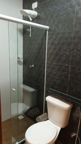 a bathroom with a toilet and a glass shower at Segunda Casa- Seu cantinho na Praia do Morro em Guarapari - Quartos suítes 2 até 4 pessoas in Guarapari