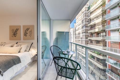 Un balcón con una cama, una mesa y sillas. en Moderno y cálido estudio en Recoleta, en Buenos Aires