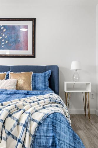 a blue bed with a blue and white comforter at LUXURY LAKEVIEW HOME - 2500sqft of private space with 5 Beds, 4 Bath, 2 Living Rooms, Kitchen, AC, Jacuzzi, 10 Guests Max, Basement Not Included, 18-min to Airport, 20-min to Downtown, 80-min to Banff in Calgary