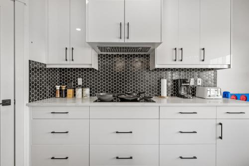 a white kitchen with white cabinets and appliances at LUXURY LAKEVIEW HOME - 2500sqft of private space with 5 Beds, 4 Bath, 2 Living Rooms, Kitchen, AC, Jacuzzi, 10 Guests Max, Basement Not Included, 18-min to Airport, 20-min to Downtown, 80-min to Banff in Calgary