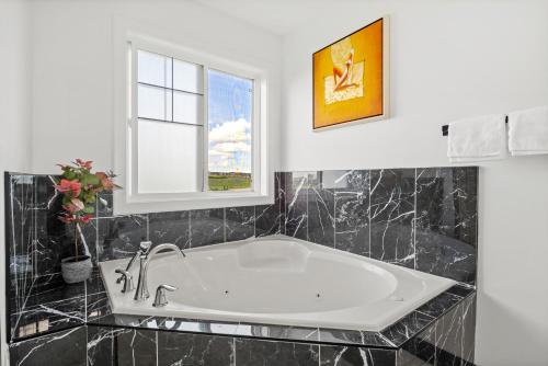 a large white tub in a bathroom with a window at LUXURY LAKEVIEW HOME - 2500sqft of private space with 5 Beds, 4 Bath, 2 Living Rooms, Kitchen, AC, Jacuzzi, 10 Guests Max, Basement Not Included, 18-min to Airport, 20-min to Downtown, 80-min to Banff in Calgary