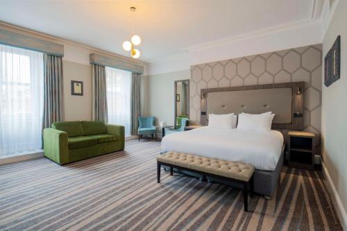 a hotel room with a bed and a green chair at The Queen at Chester Hotel, BW Premier Collection in Chester