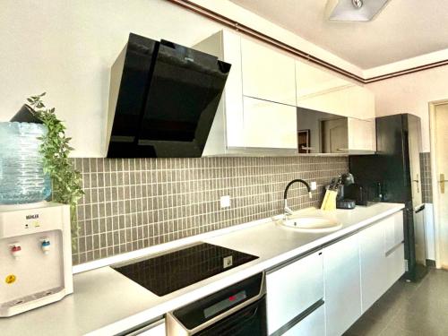 Una cocina con gabinetes blancos y un fregadero. en Apartman “Sofia”, en Pirot