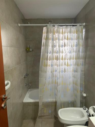 a bathroom with a shower curtain and a toilet at Montevideo Suite in Rosario