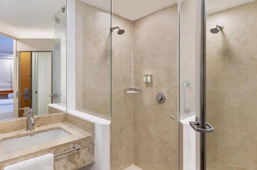 a bathroom with a glass shower with a sink at One Cuernavaca in Cuernavaca