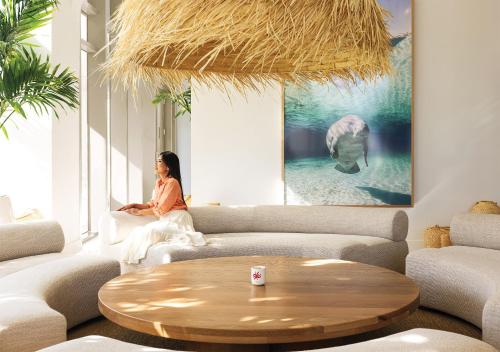 a woman sitting on a couch in a living room at Flow Hotel Miami in Miami
