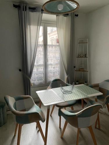 une table et des chaises dans une pièce avec une fenêtre dans l'établissement Au bas de Montmartre !, à Paris